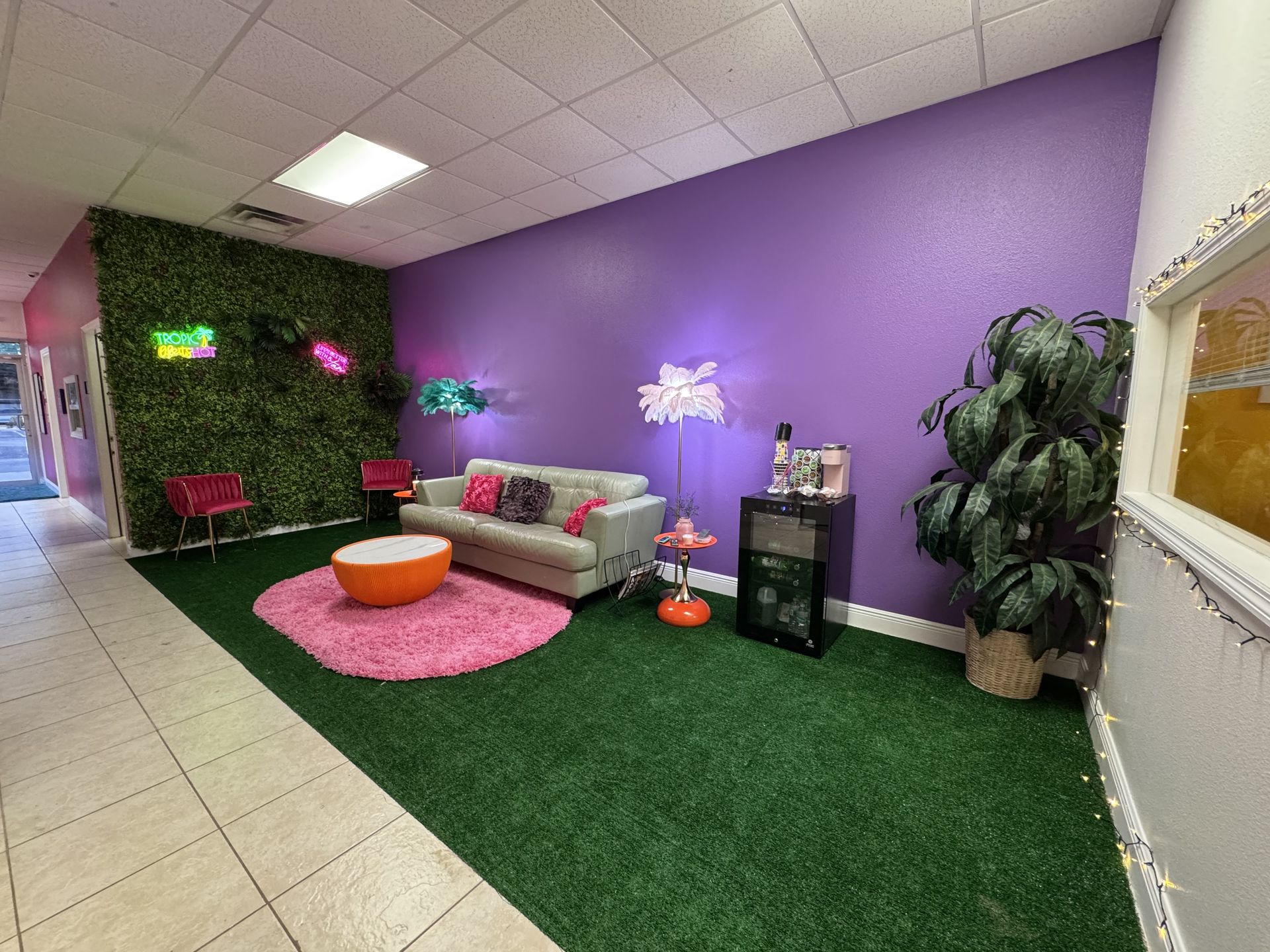 The Bronzed and Beyond lounge — purple walls, tropical greenery and neon signs